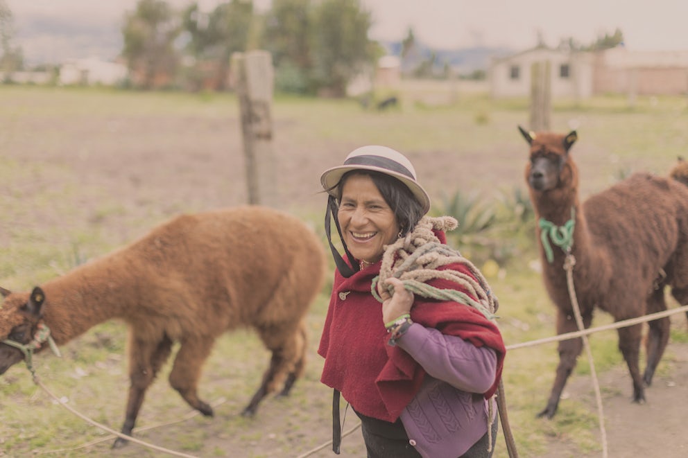 Ecuador women with alpaca in background at her farm.