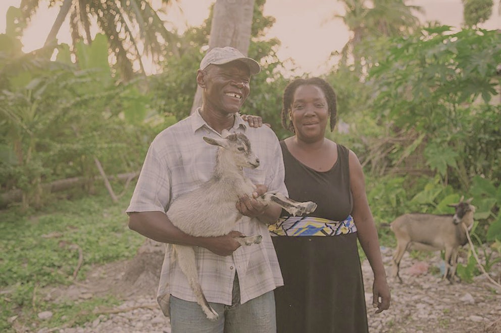 Man and woman holding a goat in Haiti.