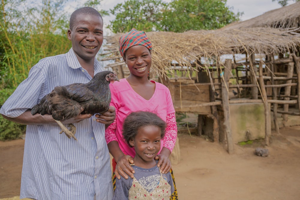 Chinzimu holds one of the family’s chickens alongside his wife, Glyceria, and their daughter, Julita.