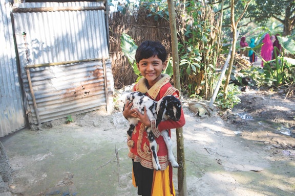 A boy holds a goat.