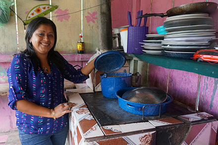 Alba proudly stands by her new stove, which she uses to cook food to sell as part of her family's business.