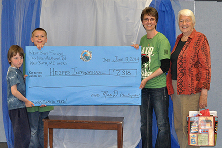 Mrs. D and Ethan present Heifer check to Jan West Schrock. Schrock's grandson, Roosevelt helps hold the check on far left.