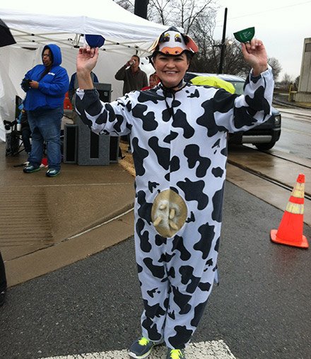 A person dressed in a cow costume cheers on runners at the Little Rock Marathon
