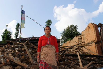 A woman stands in front of her home that collapsed in the April 25 earthquake that struck Nepal. 