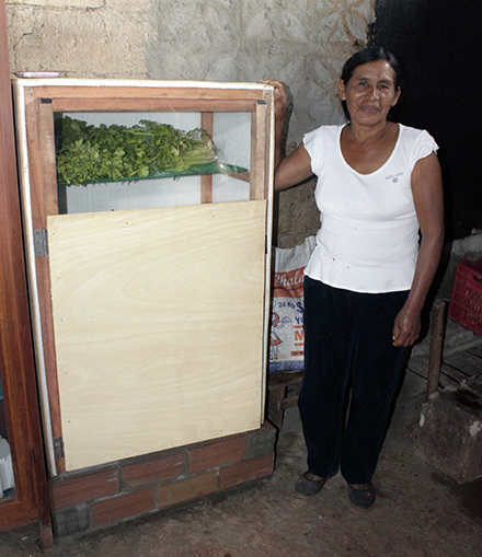 Ines stands with her ecological refrigerator. The refrigerator, which Yours learned how to build during Heifer trainings, enable her to plan meals and keep her garden vegetable fresh longer.