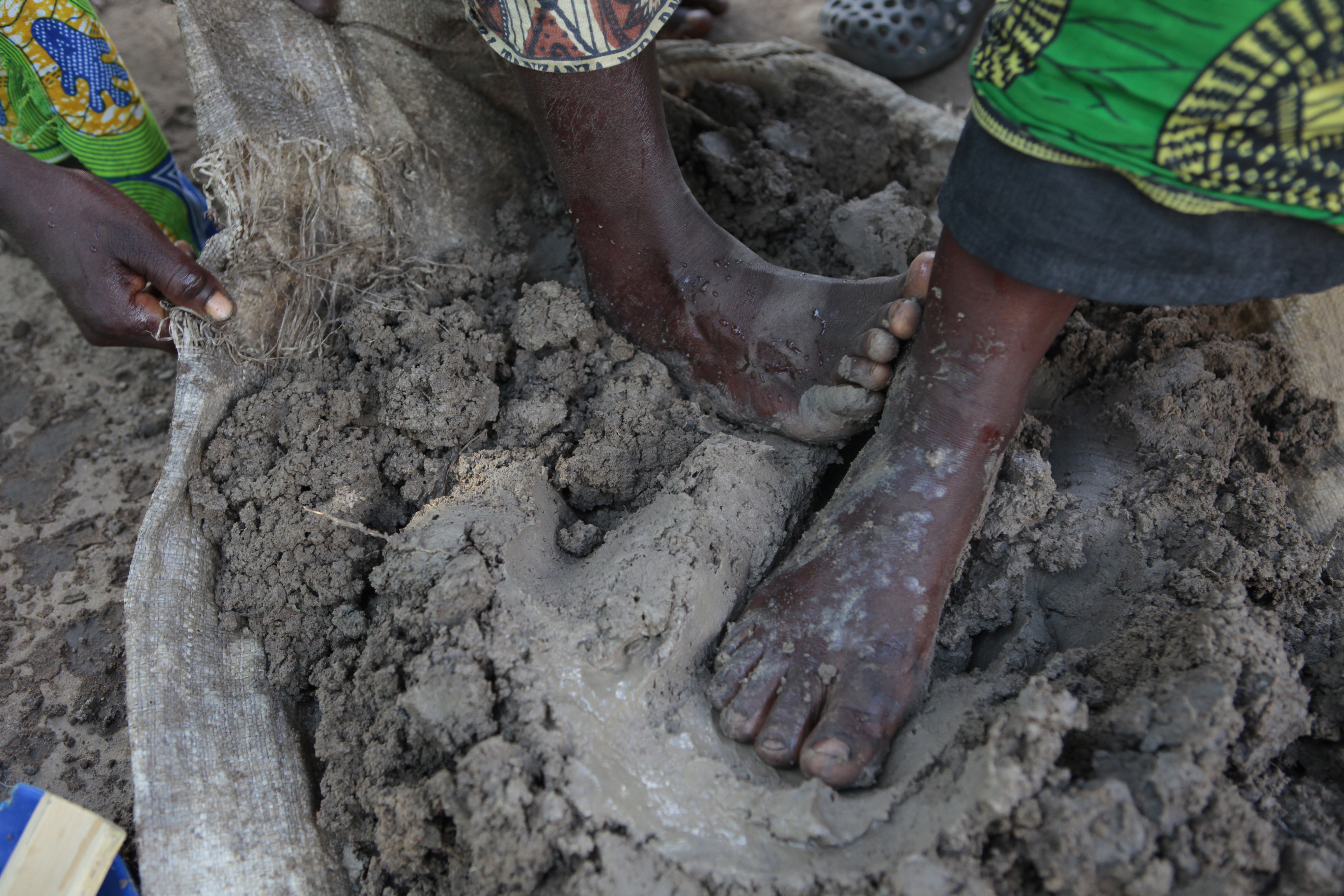Women of the Gideon village in Malawi mold clay into portable clay stoves with their hands and feet.