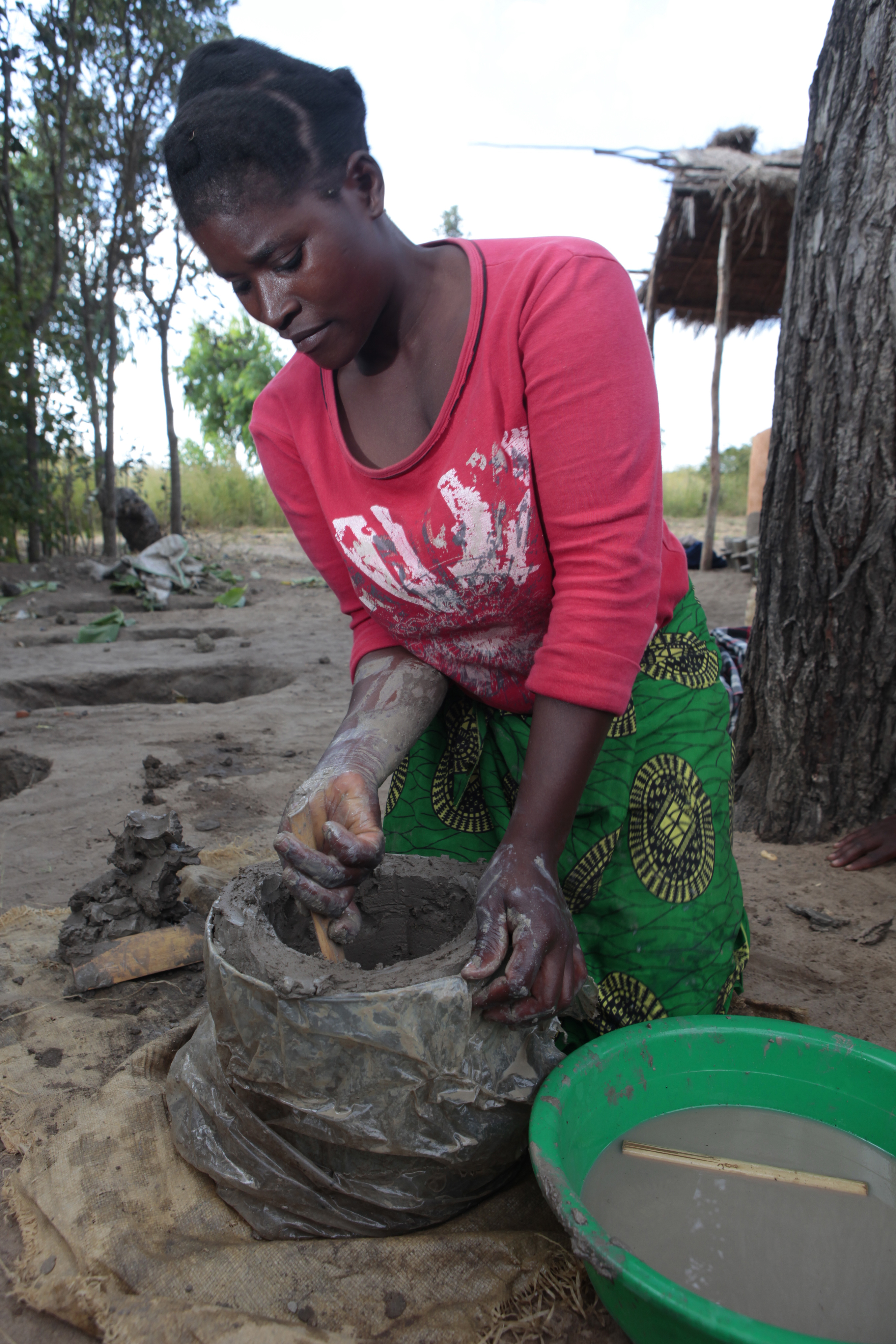 Sharon Nkhoma, 27 years old, molds a clay stove. 