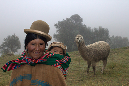 Mother and child pose while menacing llama lurks in the background.
