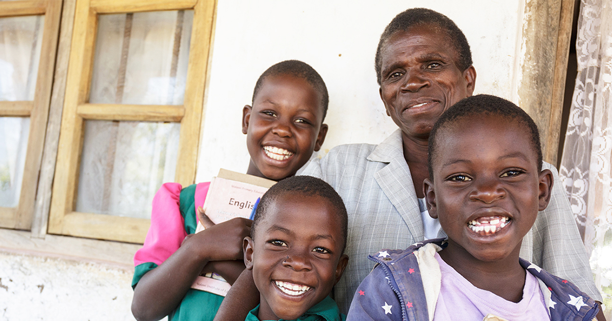 A grandmother poses with her three smiling grandchildren.