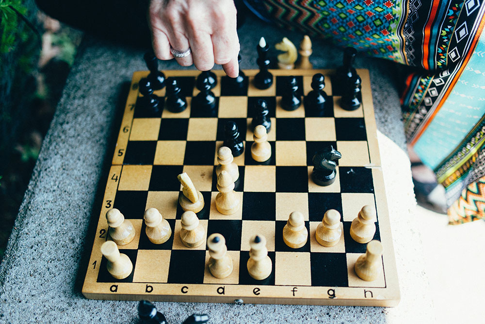 A chess board with a woman's hand moving a piece.