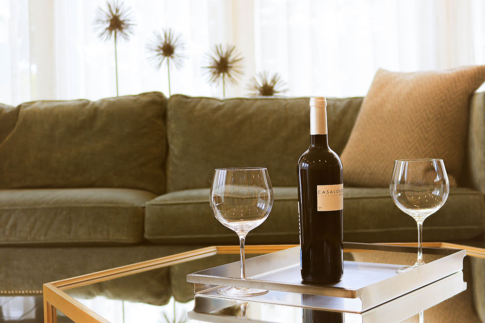 A couch with two wine glasses on a table.