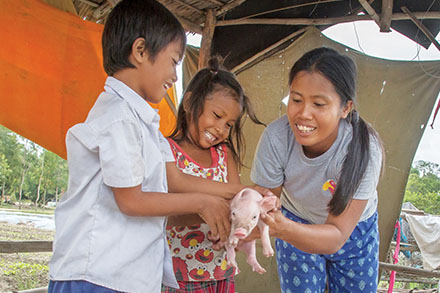Ou Kongkea with her children taking care of their pigs.