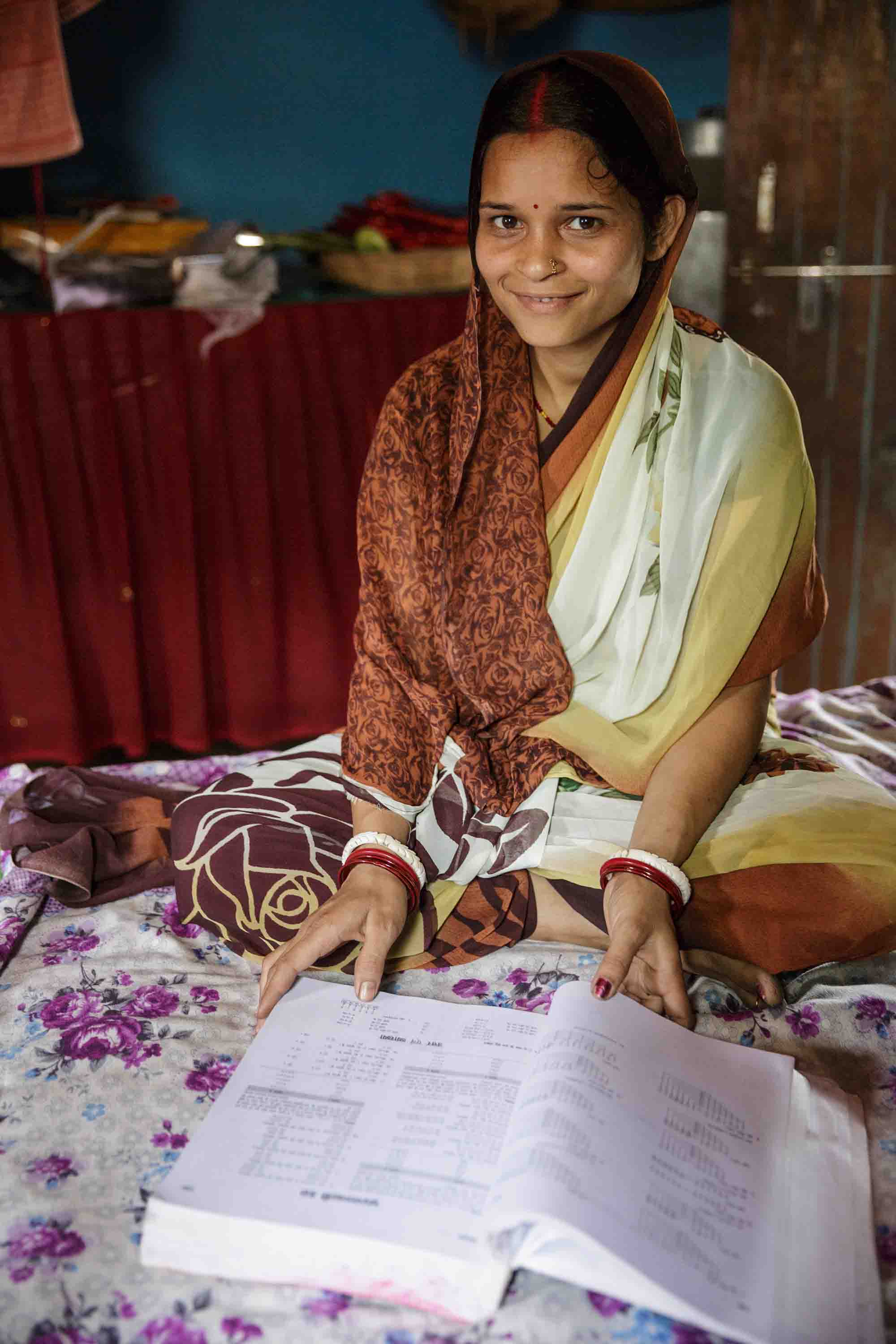 Puja Kumari sits on her bed with one of her textbooks.