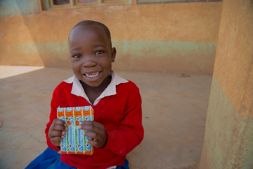 Isabel Sambanae drinking out of a milk packet at school in Tanzania. Heifer works with dairy farmers who are providing milk for school children in the East African country.