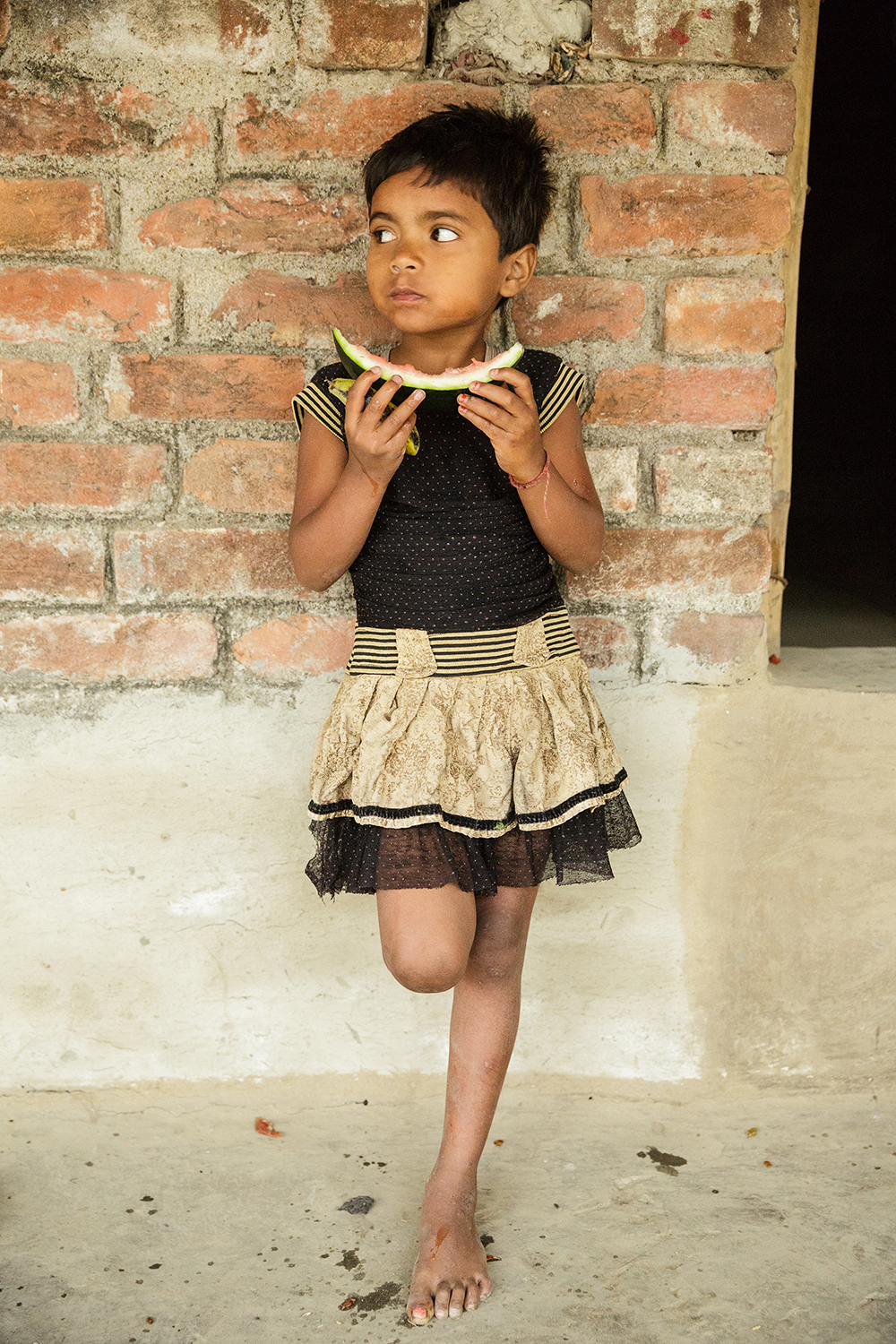 A young Indian girl eats a slice of watermelon.