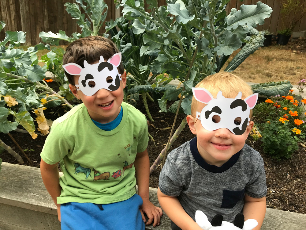 Two boys wear cow masks.