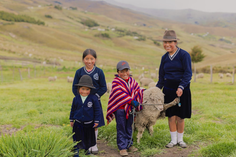 Ashley Ximena (4), Ariel Jesús (10), Margarita Elizabeth (14), and Enma Tatiana (12) pose for with one of their sheep. Ashley and Margarita are sporting chic hats with their school uniforms.