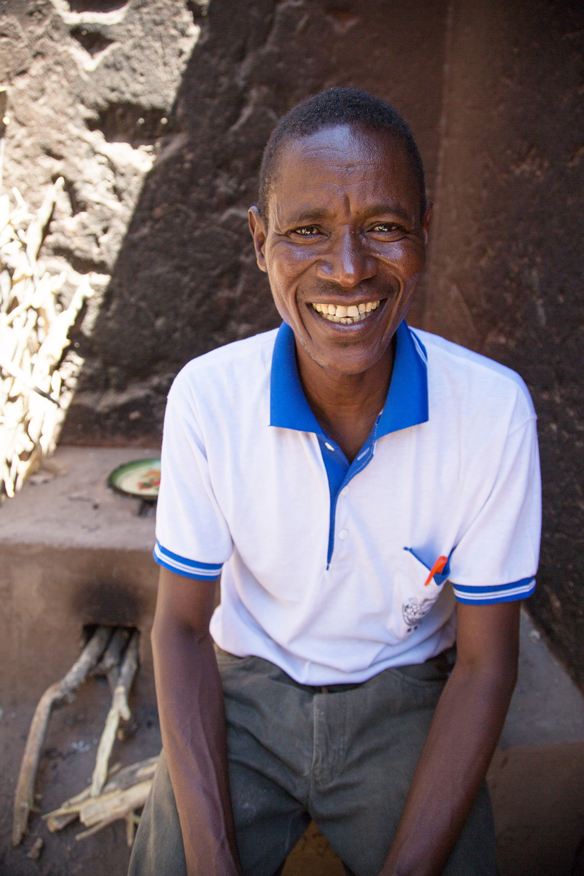 Socha sits smiling on the improved stove he built for Stella.