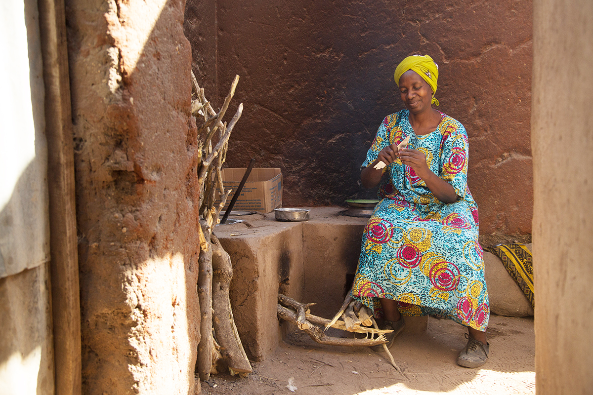 Stella sits near her stove preparing onions for a meal.