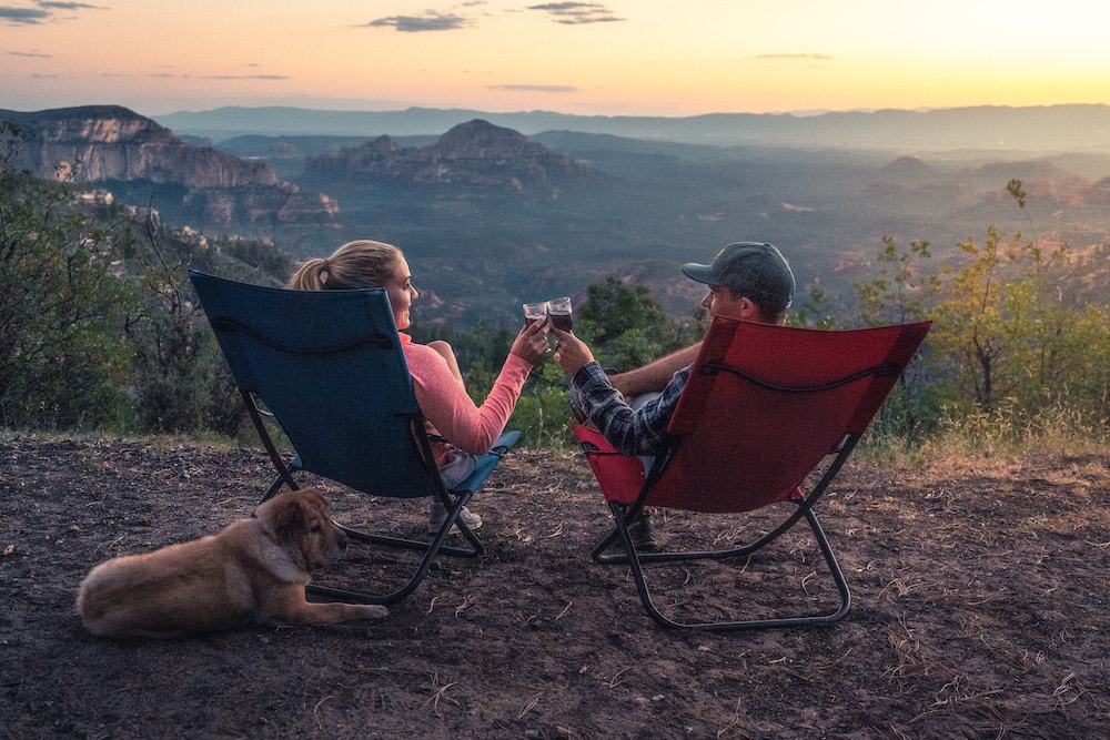 Two campers cheers in front of a canyon vista.