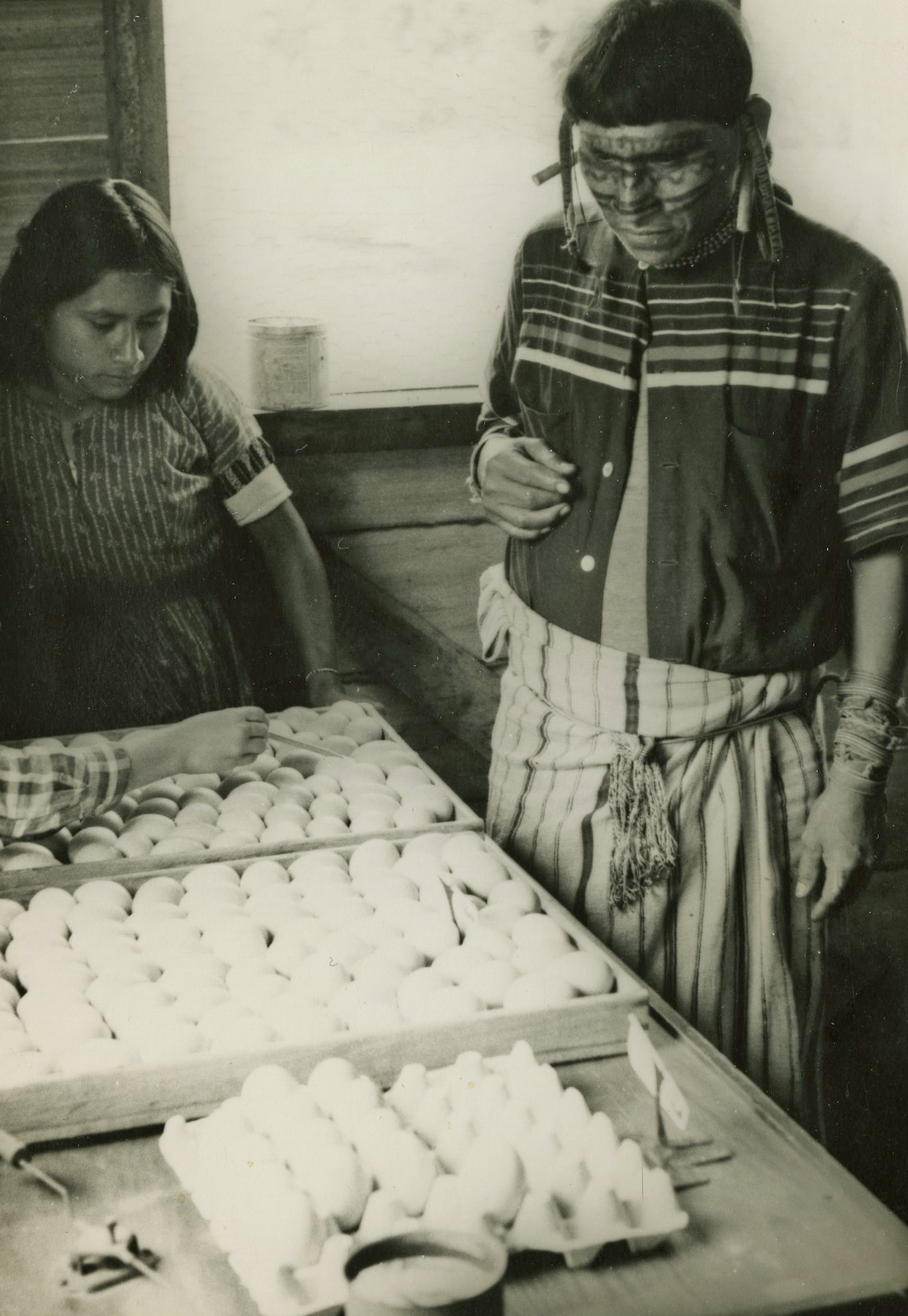 Two native Bolivians examine a crate of eggs.