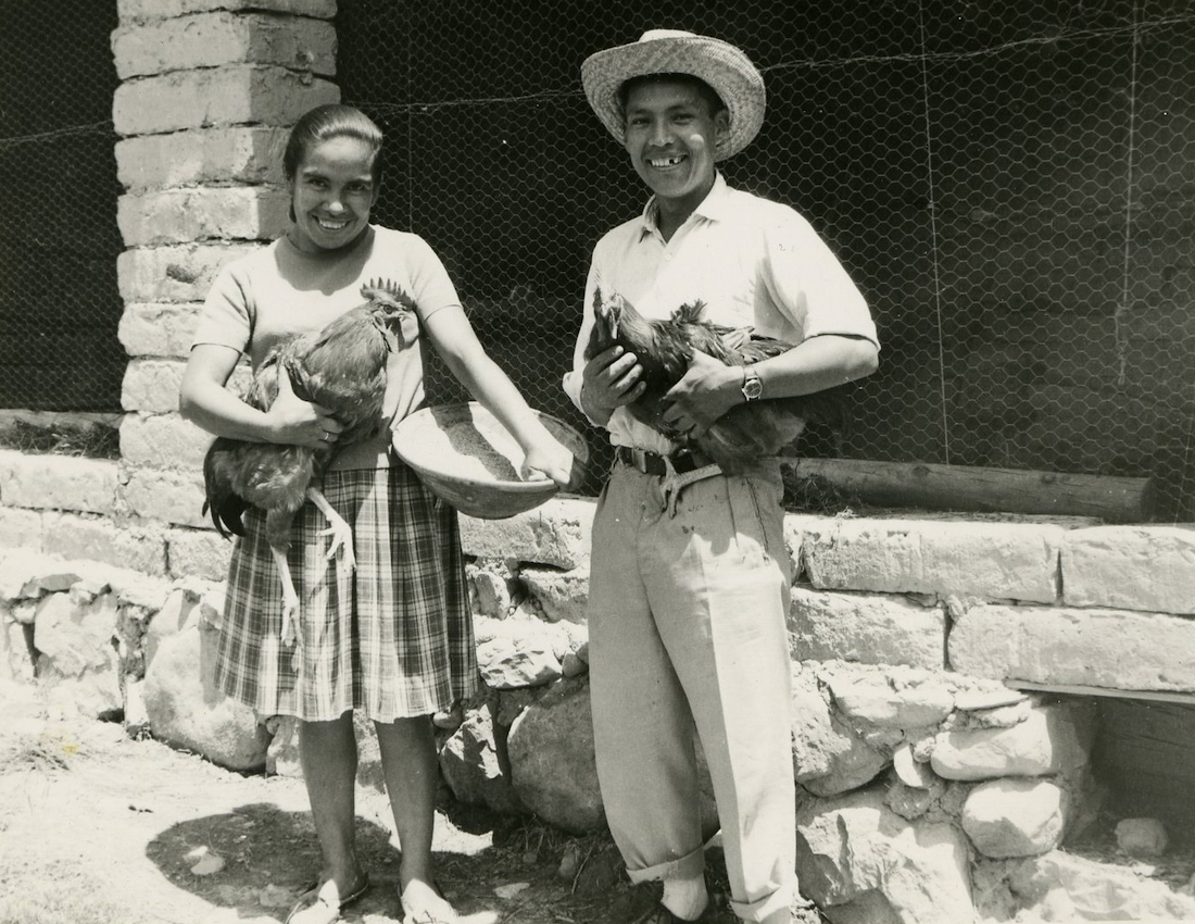 A native Bolivian man and woman smile while they hold chickens.