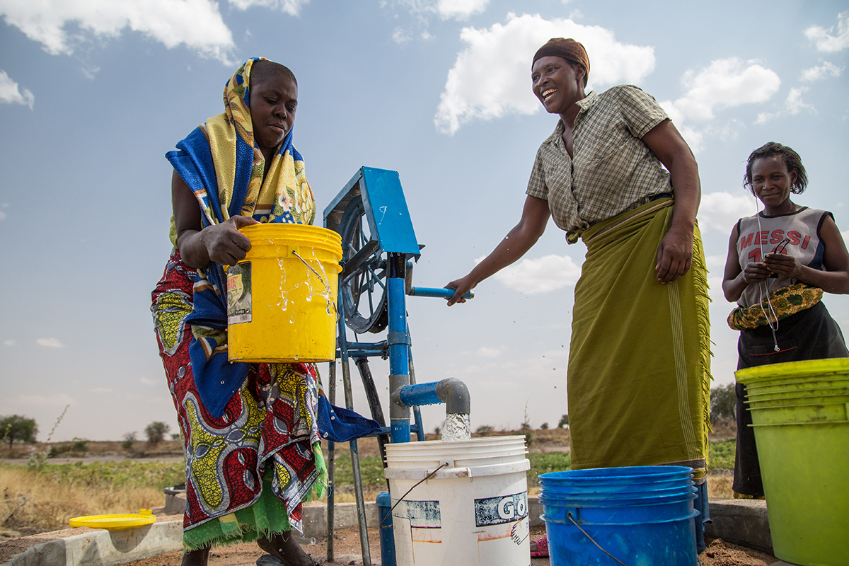 A group of neighbors gather at a newly opened shallow well.