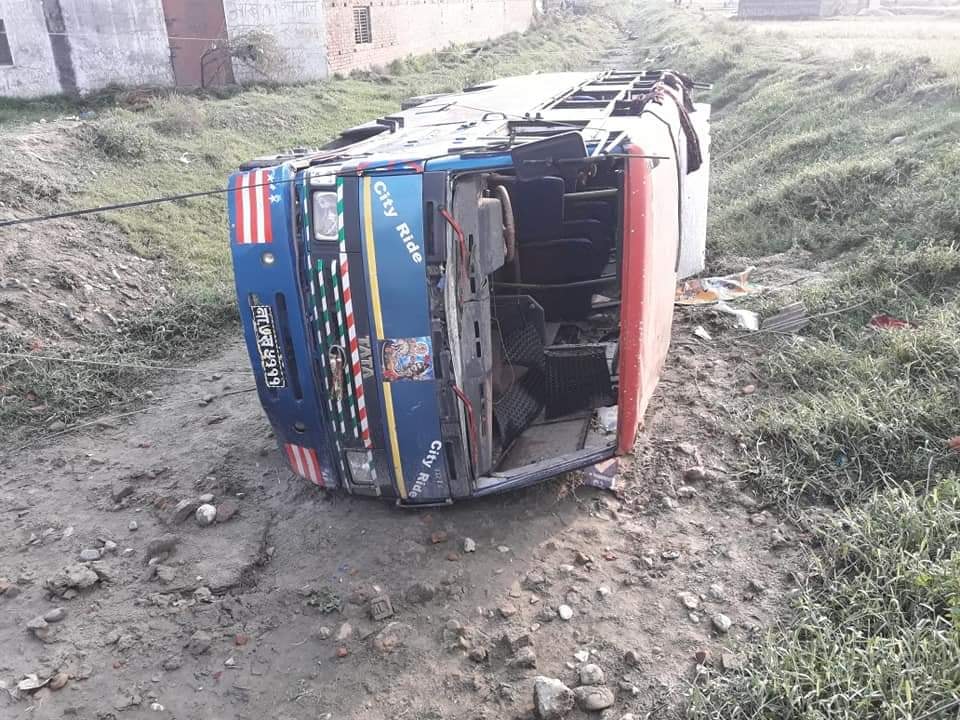A bus turned on its side on a dirt road.