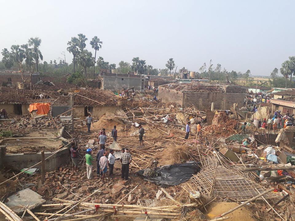 Scattered groups of victims observe their demolished neighborhood.