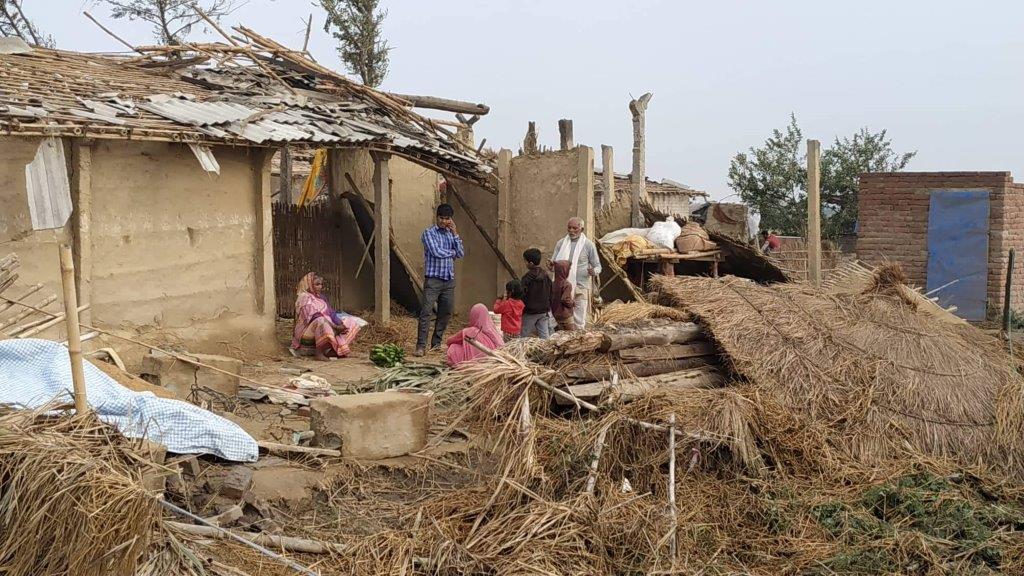 A family looks solemnly upon their caved in home.