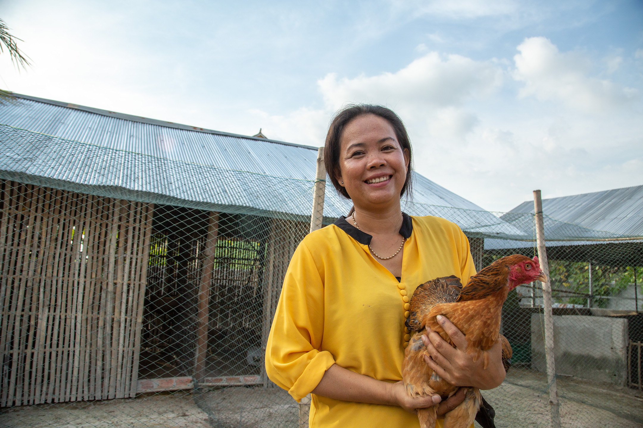 Hoy Lin smiles while she holds a chicken.