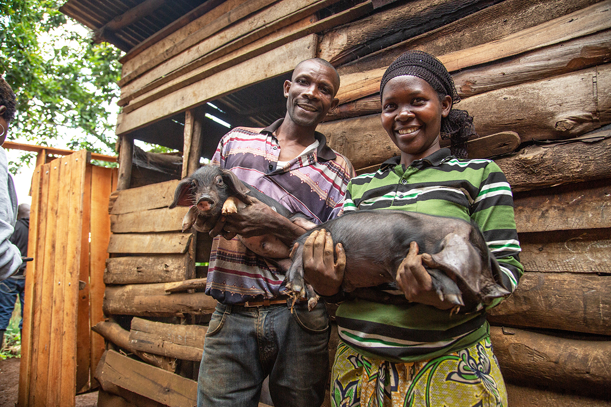 Mary Rose and her husband Fidel hold two pigs.