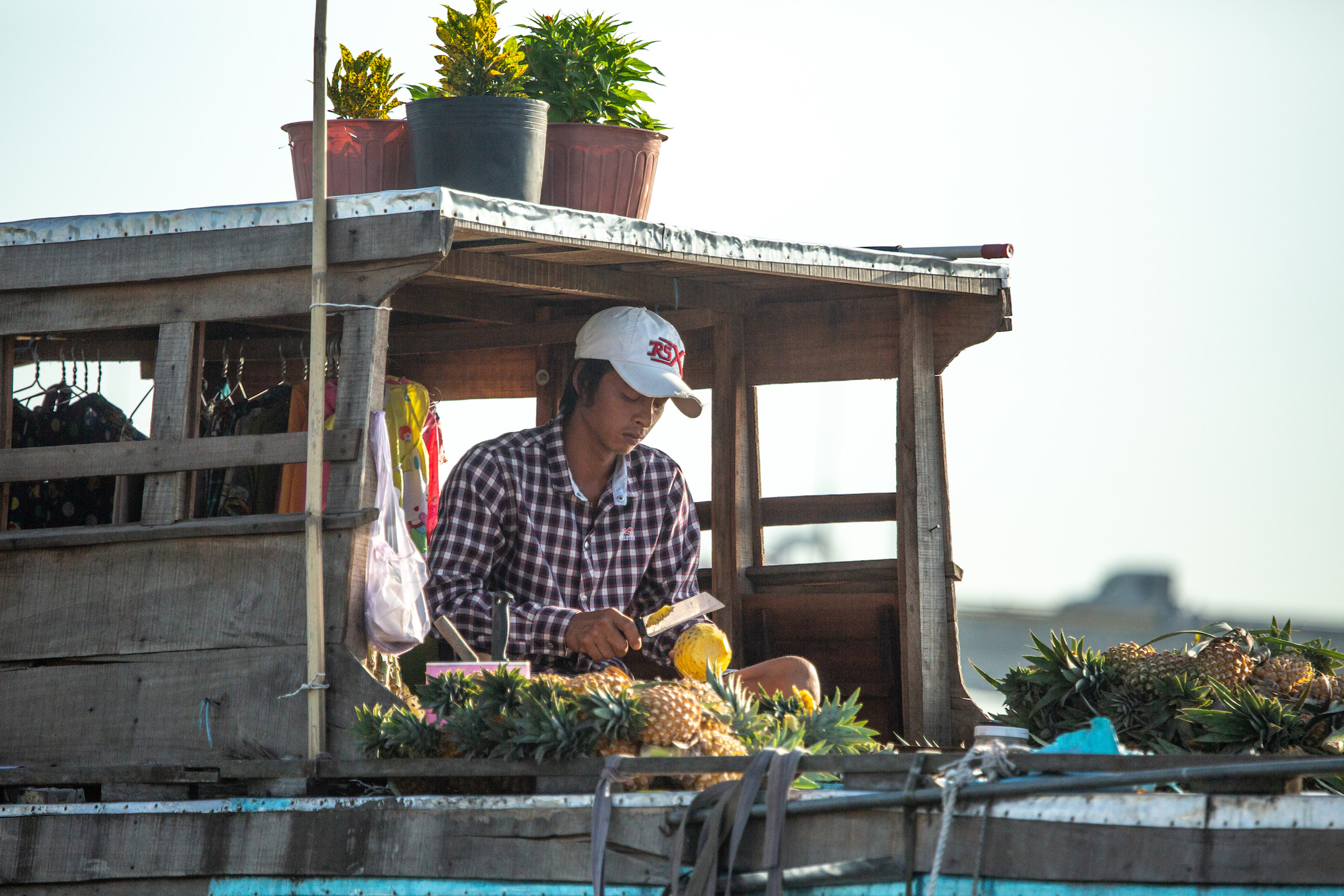 A young man chops fresh pinapple at a booth.