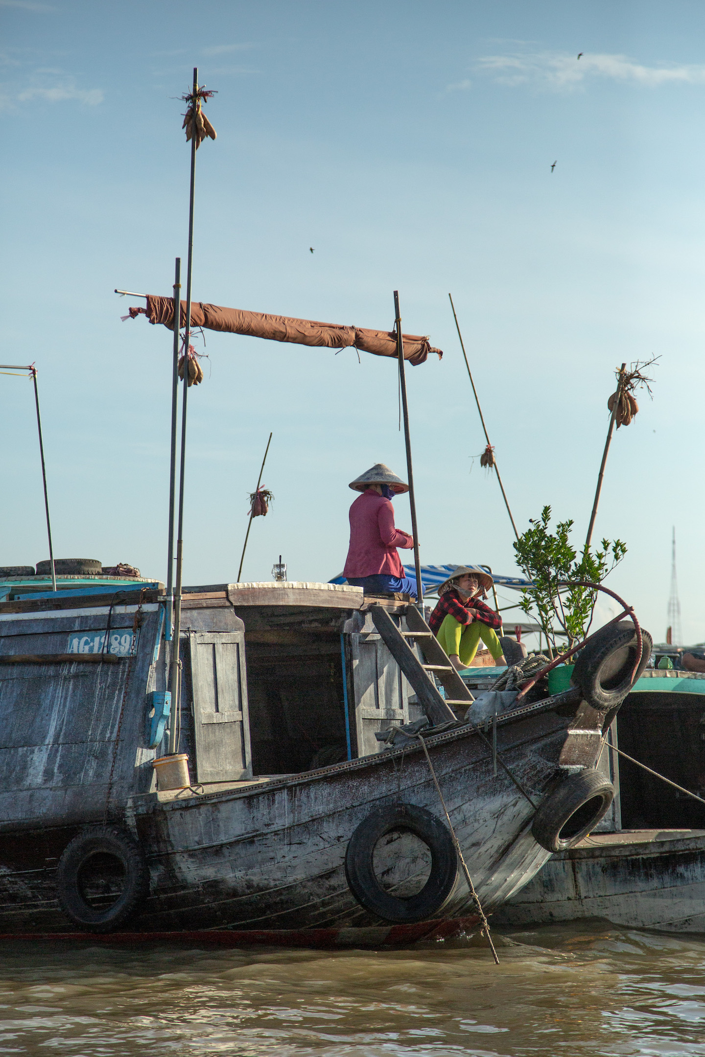 Vendors display their goods atop tall bamboo poles on their boats.