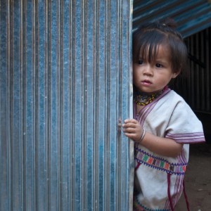 A Karen girl from Sa-ngin Klang Village in Thailand peers around the wall of her family's new toilet room.