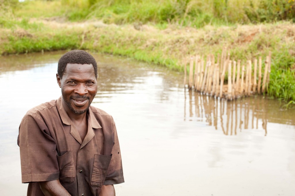 Nicholas Mwakabelele in front of his tilapia pond.