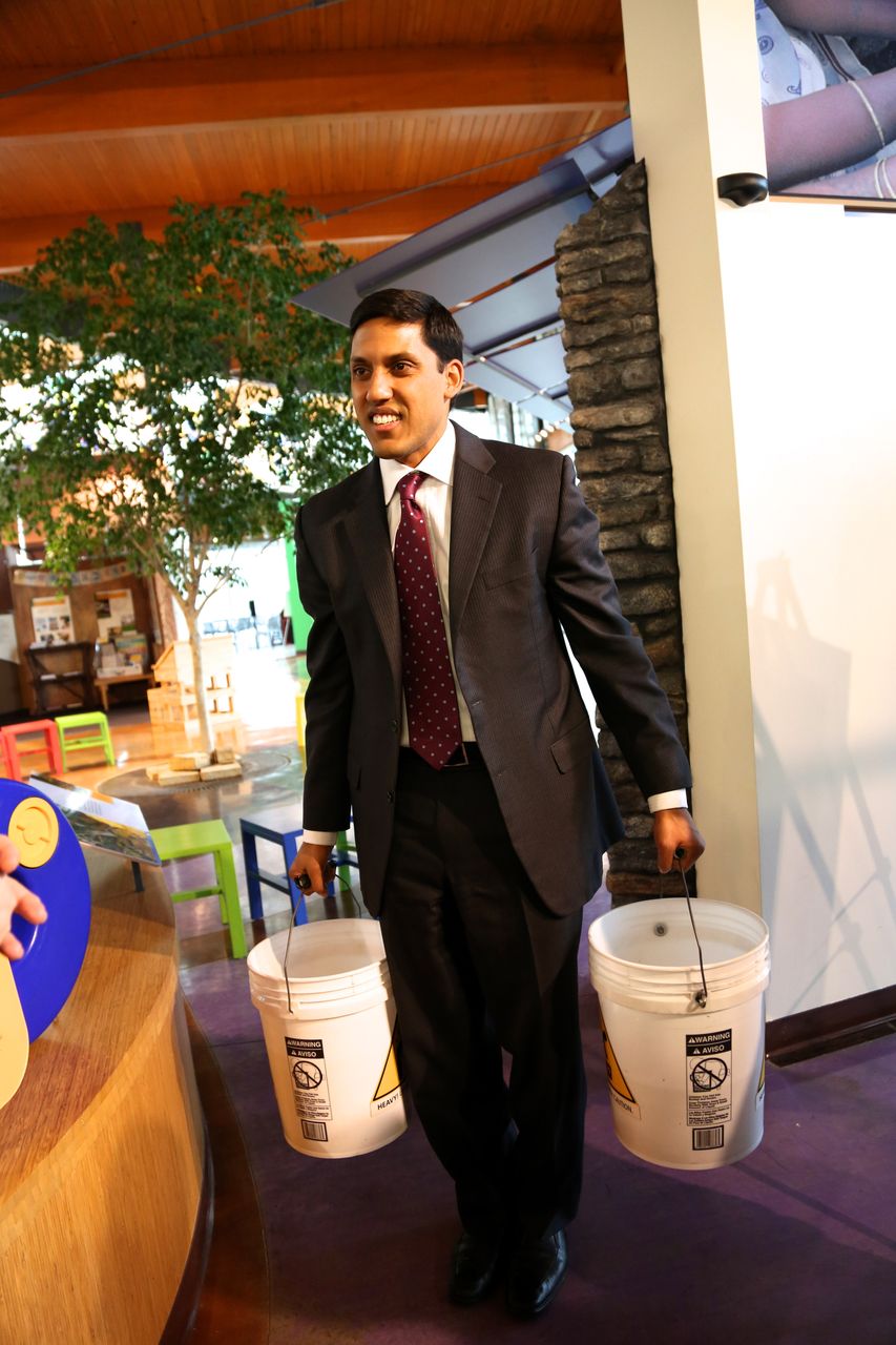 Raj Shah, USAID Administrator, holds weighted water buckets used to demonstrate to Heifer Village visitors the heavy burden of fetching water daily.