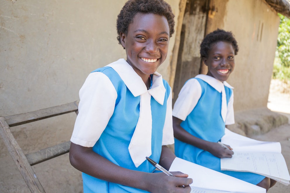 Emmy and her cousin work in their school books as they sit outside their home