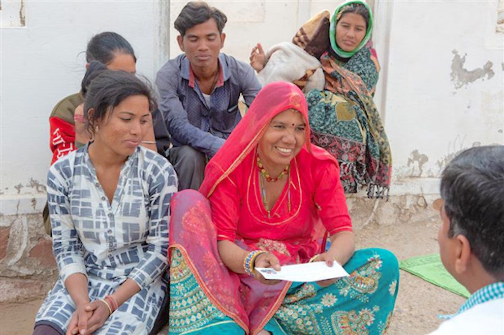 woman reading note to others in her village