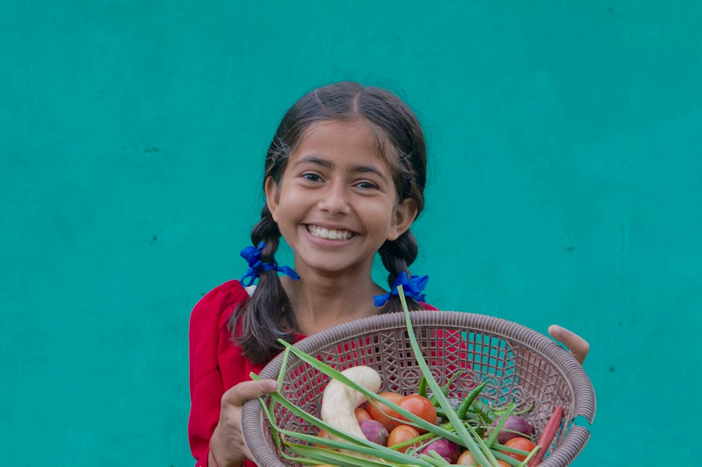 Child in Nepal holding vegetables