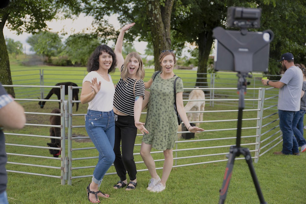 Three women posing for a photo in front of llamas at Heifer.