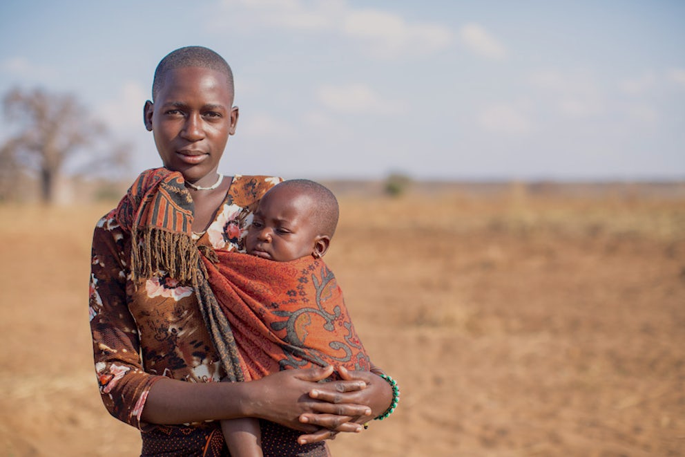 mother with a baby in a sling on her hip posing for the camera