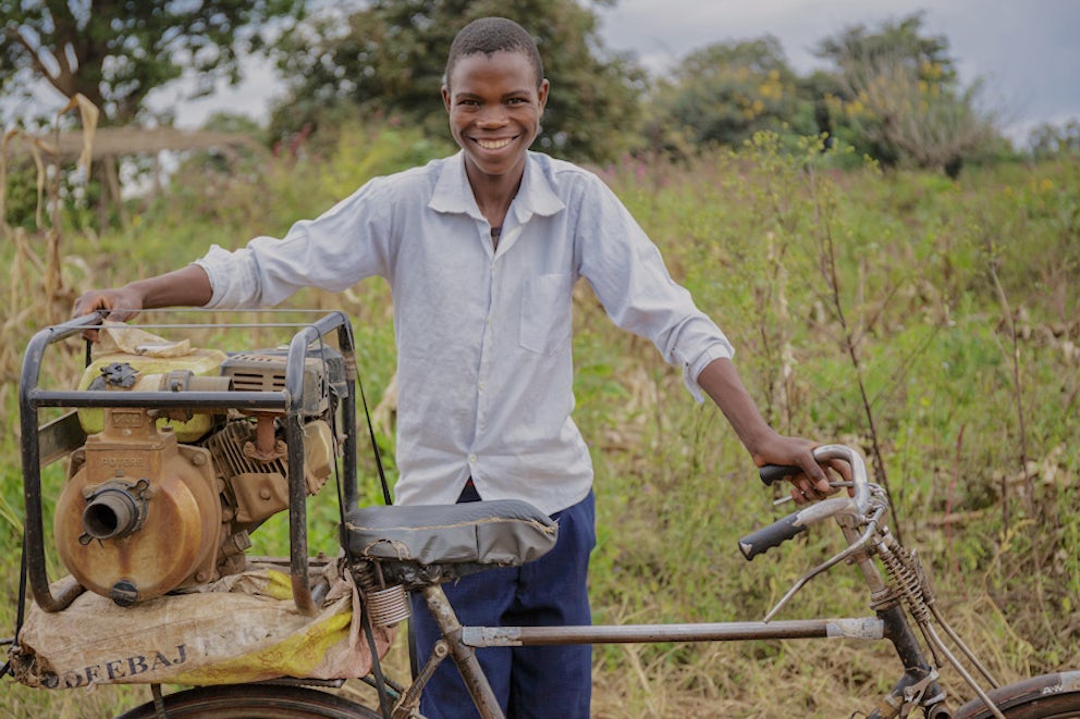 man transporting an irrigation pump on his bike