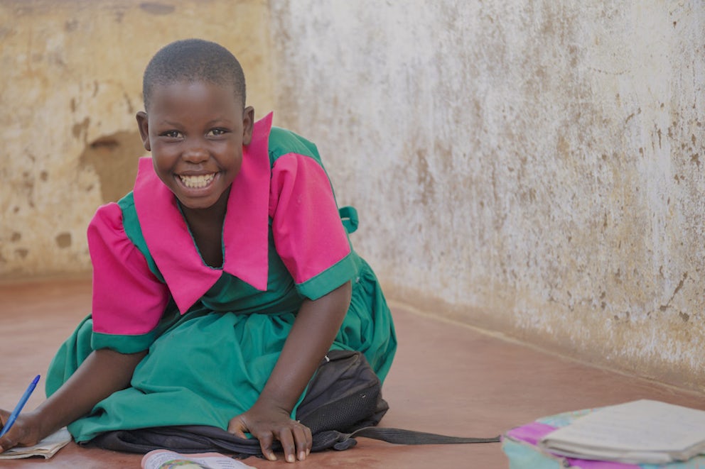 Girl smiling, happy because they are able to attend school due to gifts received from Heifer International