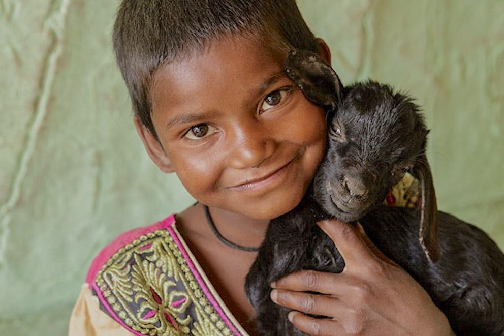 girl holding a goat and smiling