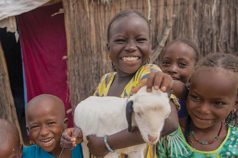 Khardiata holding a lamb, surrounded by a group of children.