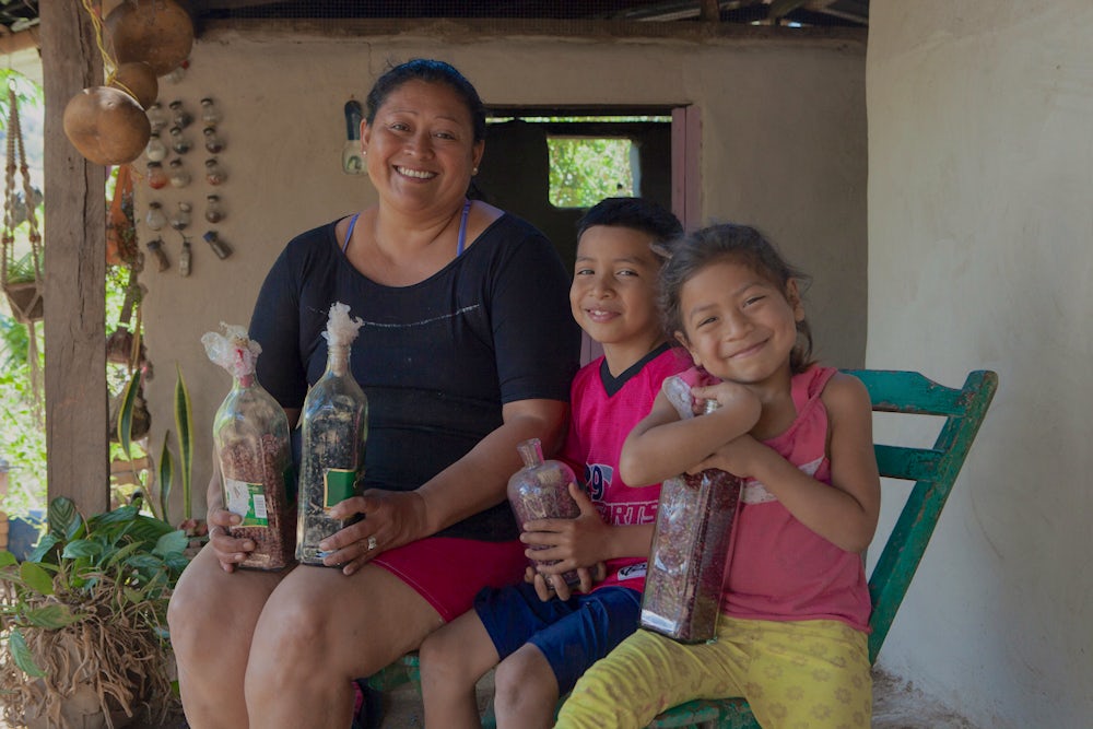 Santos and her grandchildren Joesan and Nayisha hold bottles of stored beans.