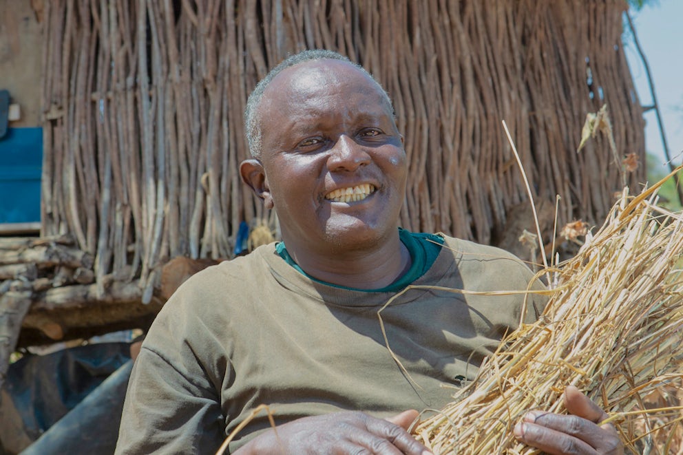 Benjamin Musembi Kyengo holds grass outside his home in Mangauni B village, Kenya.