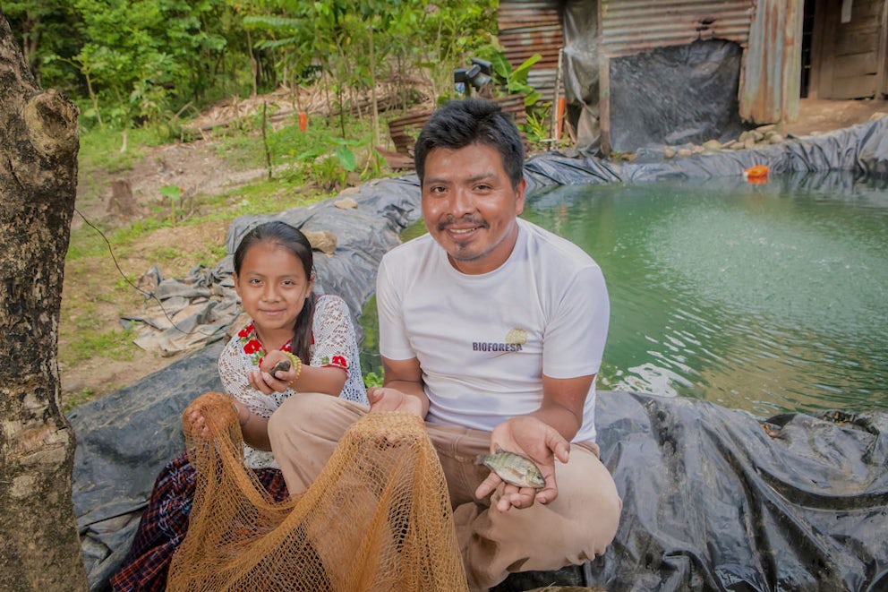 Zacarías Xol Cuc and his daughter in front of their fish pond