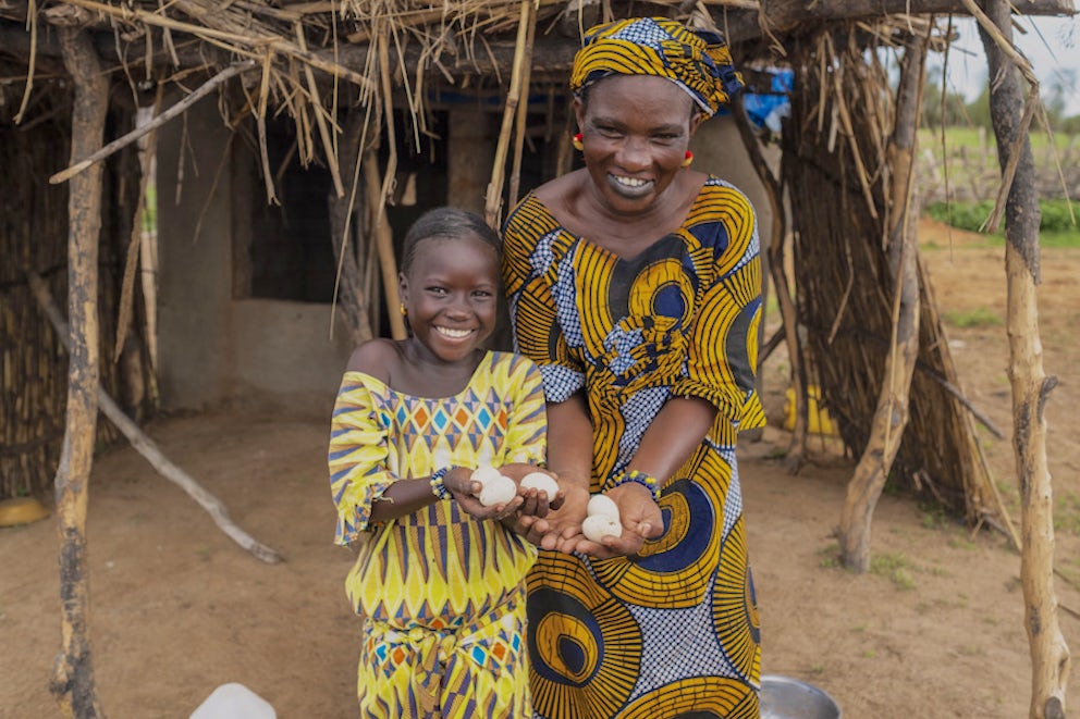 Khardiata and her mother pose for a portrait holding some eggs they collected